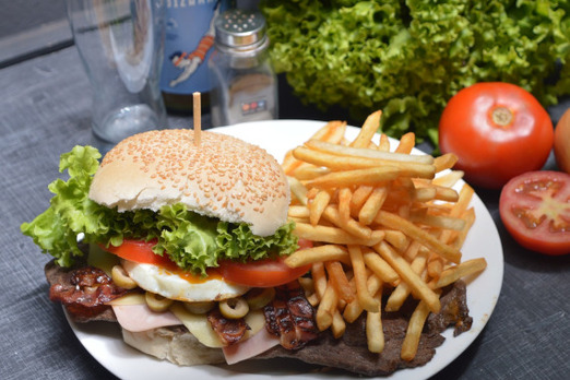 Burger mit Salat, Tomaten und Pommes auf einem Teller