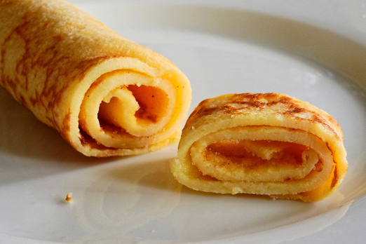 Gerollter Pfannkuchen mit süßer Füllung auf einem Teller