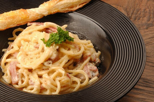 Spaghetti in cremiger Sauce mit Garnelen und Kräutern auf einem Teller